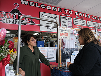 Owner of Sylmar-based Swiss Cleaners, Isabel Vides (left) chats with a customer at her shop counter